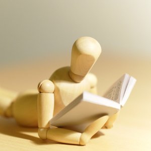 Manequin en bois en position de lecture